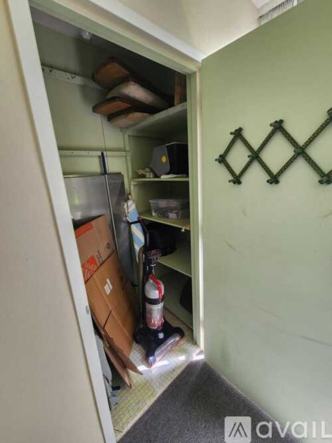 A small kitchen with a refrigerator and a bottle on the floor.