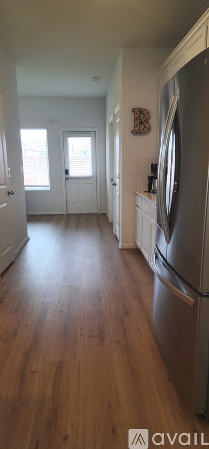 A kitchen with a refrigerator and wooden floors.