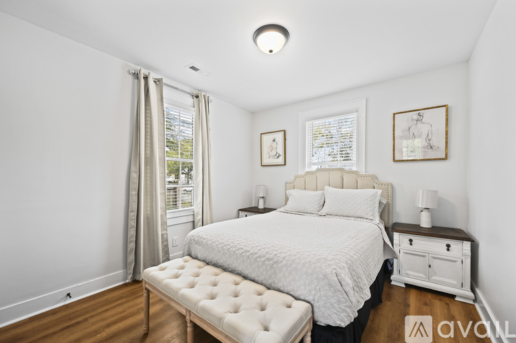 A bedroom with a large bed, a bench, and two pictures on the wall.