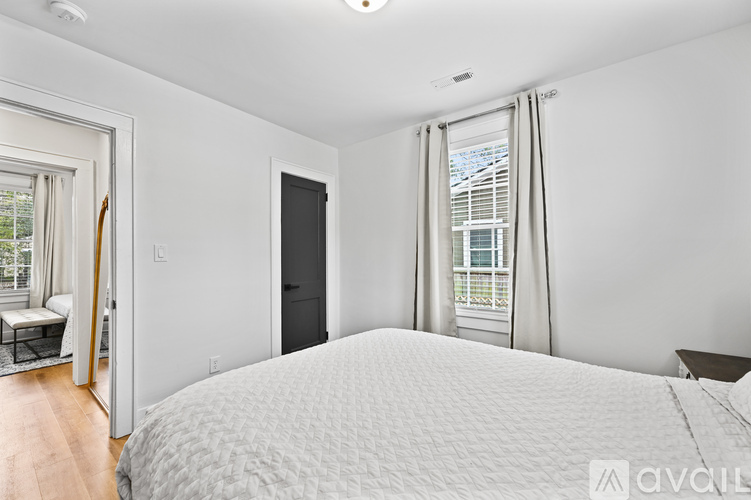 A bedroom with a large bed and a window with curtains.