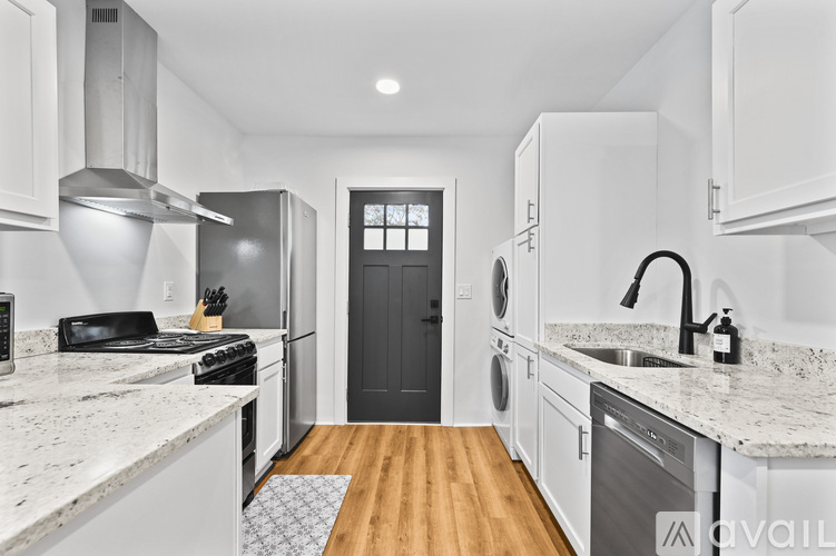 A modern kitchen with white cabinets and a black door.