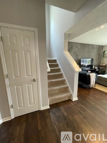 A white door is open to a living room with a couch and a television.