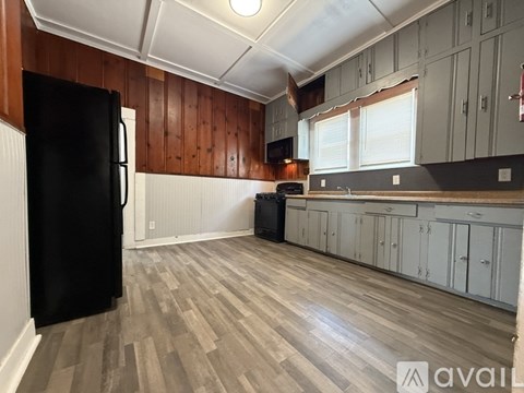 A kitchen with wooden cabinets and a black fridge.