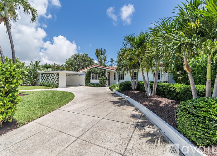 A house with a driveway and palm trees in front.