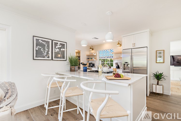 A kitchen with a table and chairs in the foreground and a refrigerator in the background.