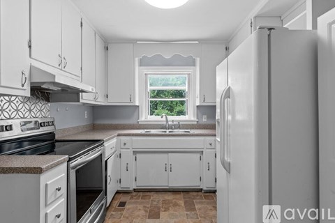 A kitchen with white cabinets and a window.