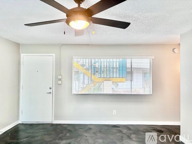 A room with a ceiling fan and a window with blinds.