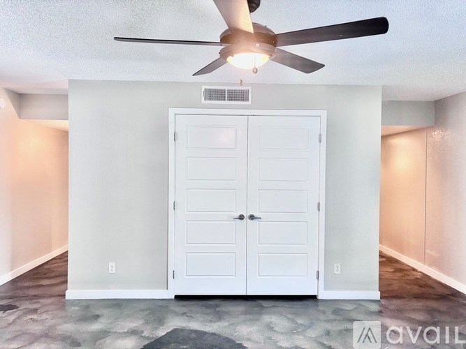 A room with a ceiling fan and a white door.