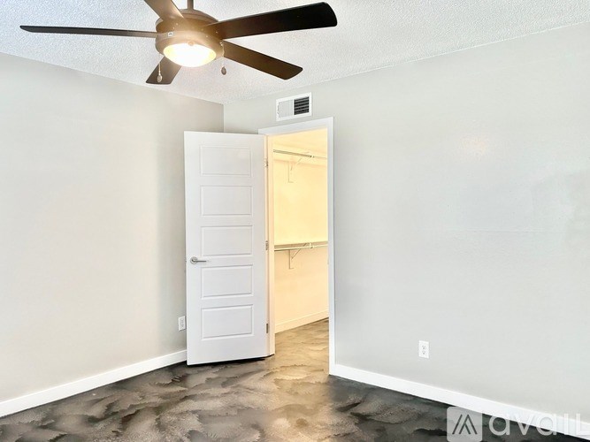 A room with a ceiling fan and a door leading to another room.