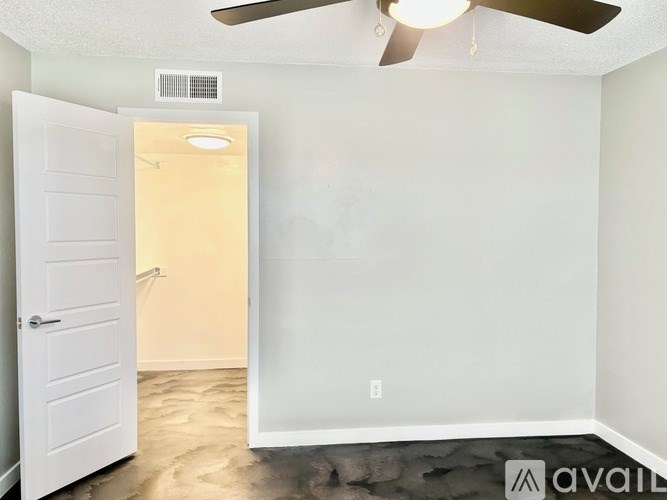 A room with a ceiling fan and a door leading to another room.