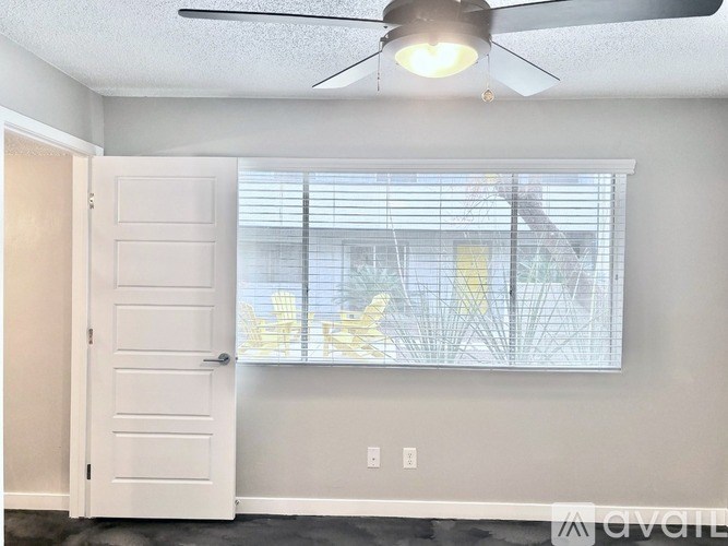 A room with a ceiling fan and a window with blinds.