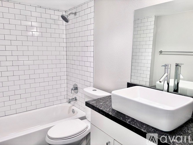 A white bathroom with a black counter top and a white toilet.