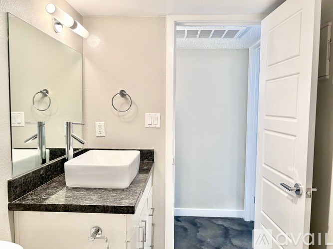 A bathroom with a sink, mirror, and lighting fixtures.