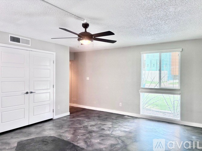 A room with a ceiling fan and a large window.