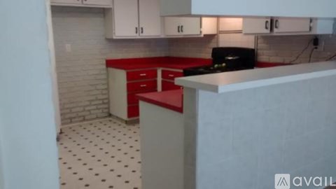 A kitchen with a red counter and white cabinets.