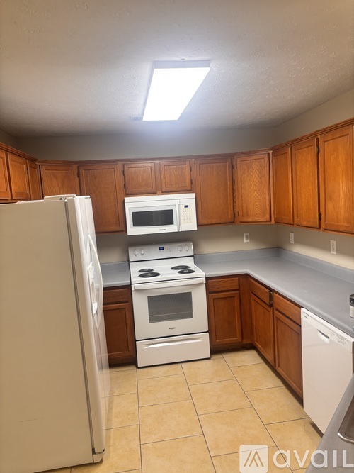 A kitchen with white appliances and wooden cabinets.