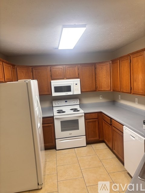 A kitchen with white appliances and wooden cabinets.