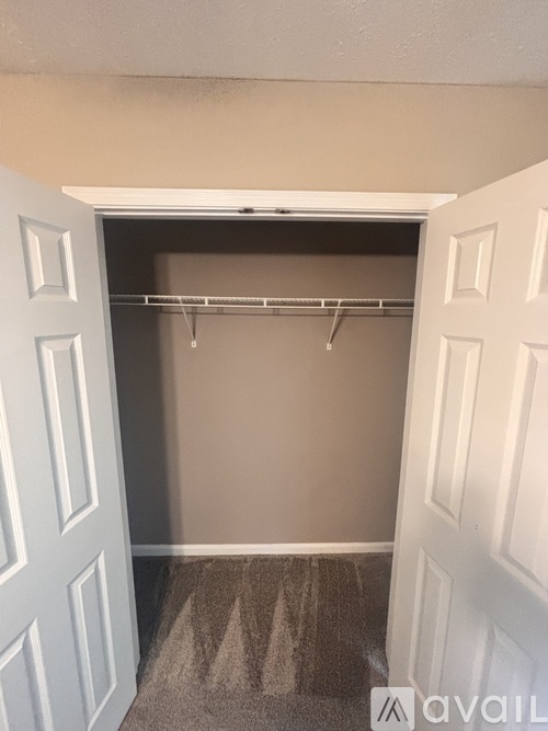 A white door is open to a closet with a metal rod.