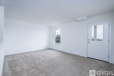 A spacious room with a door, a window, and a refrigerator.