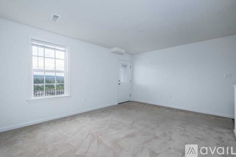 A room with a window and a carpeted floor.