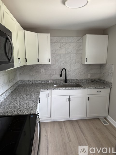 A kitchen with white cabinets and a black oven.
