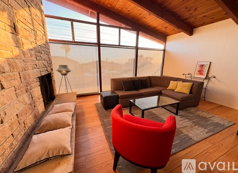 A living room with a red chair and a brick wall.