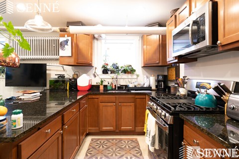 A kitchen with wooden cabinets and black countertops.