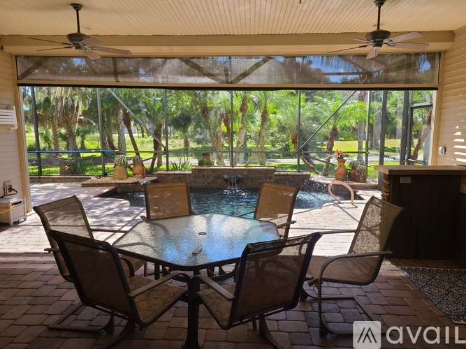 A patio with a table and chairs overlooking a pool.