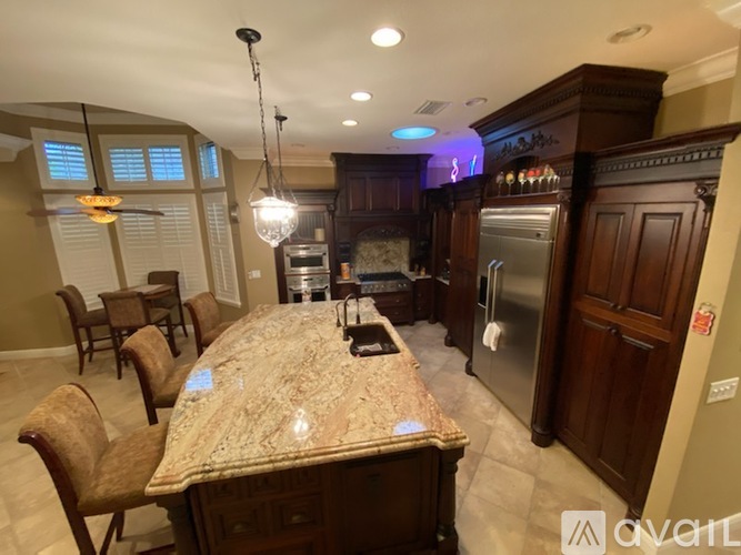 A kitchen with a marble countertop and a dining table with chairs.