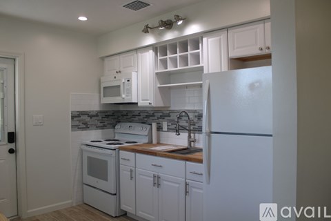 A kitchen with white cabinets and appliances.