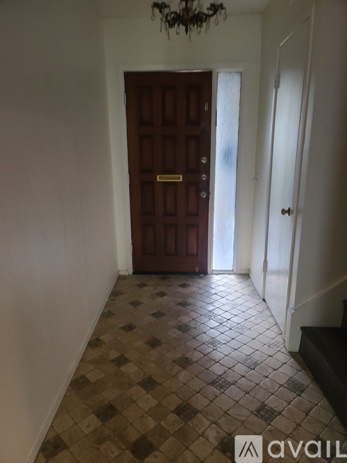 A hallway with a brown door and a tiled floor.