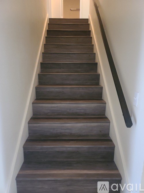 A set of stairs with a black handrail.
