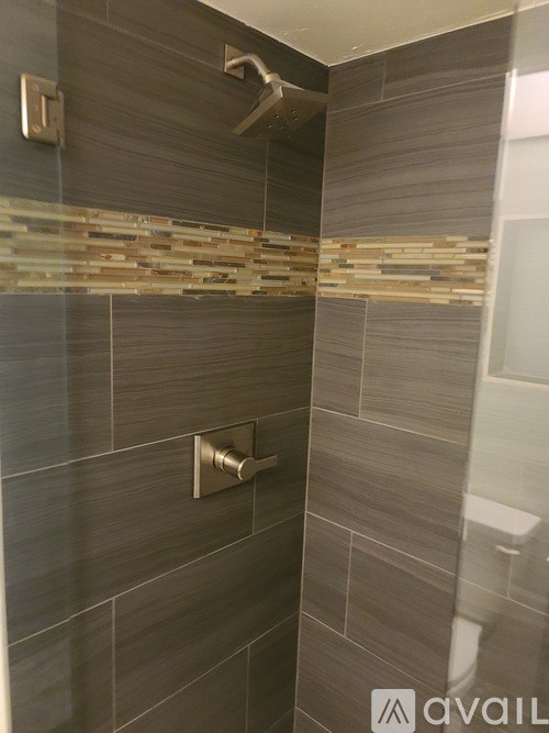 A bathroom with a shower head and a wall of tiles.