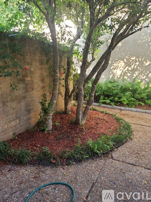 A garden with a red mulch bed and a tree in the middle.