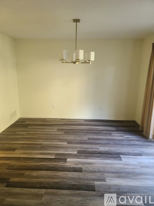 A room with a wooden floor and a chandelier hanging from the ceiling.