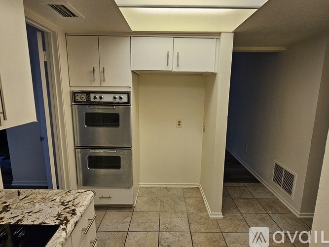 A kitchen with a stainless steel oven and white cabinets.