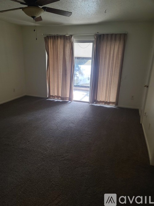 A room with a ceiling fan and a window with curtains.