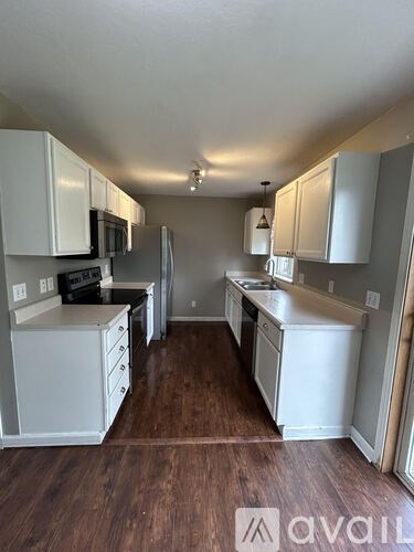 A kitchen with white cabinets and a wooden floor.