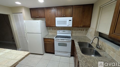 A kitchen with a white refrigerator, a white oven, a white microwave, and a sink.