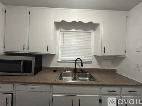 A kitchen with white cabinets and a brown countertop.