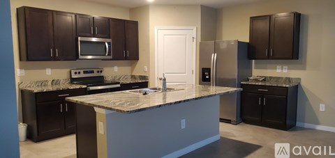 A kitchen with dark brown cabinets and a granite countertop.