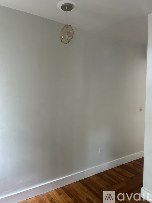A room with a wooden floor and a light hanging from the ceiling.