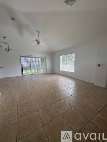A spacious room with tiled flooring and a ceiling fan.