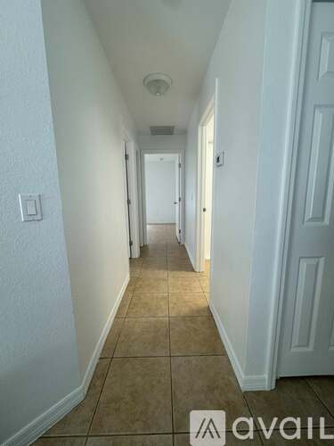 A long hallway with white walls and a tiled floor.