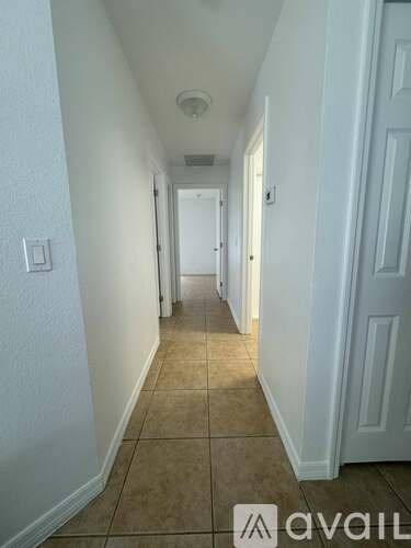 A long hallway with white walls and a tiled floor.