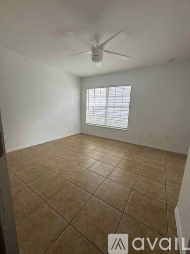 A room with a ceiling fan and a window with blinds.