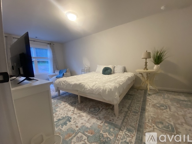 A modern bedroom with a large bed, a chair, and a sign that says "coming soon".