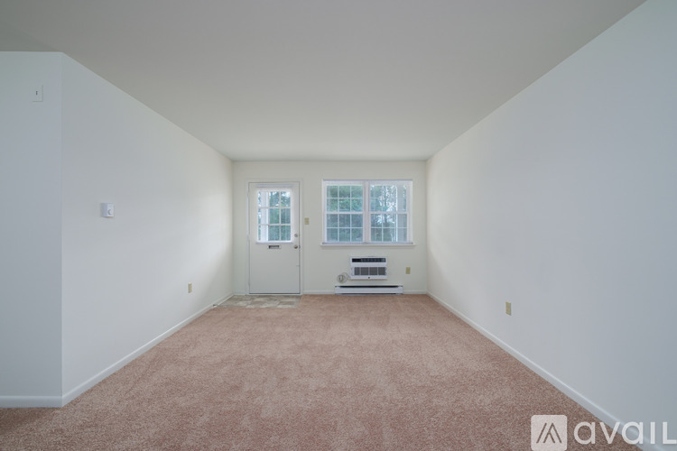 A room with a carpeted floor and a window with blinds.
