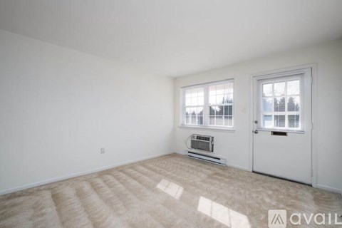 A room with a carpeted floor and a window with blinds.
