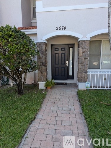 A house numbered 2574 with a black door and a tree in front.